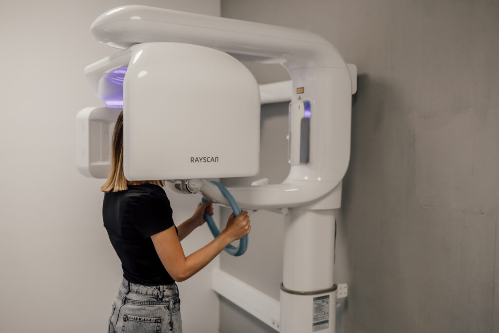 Patient passant un examen CBCT low dose dans un cabinet dentaire moderne, avec reconstruction 3D des mâchoires affichée à l'écran