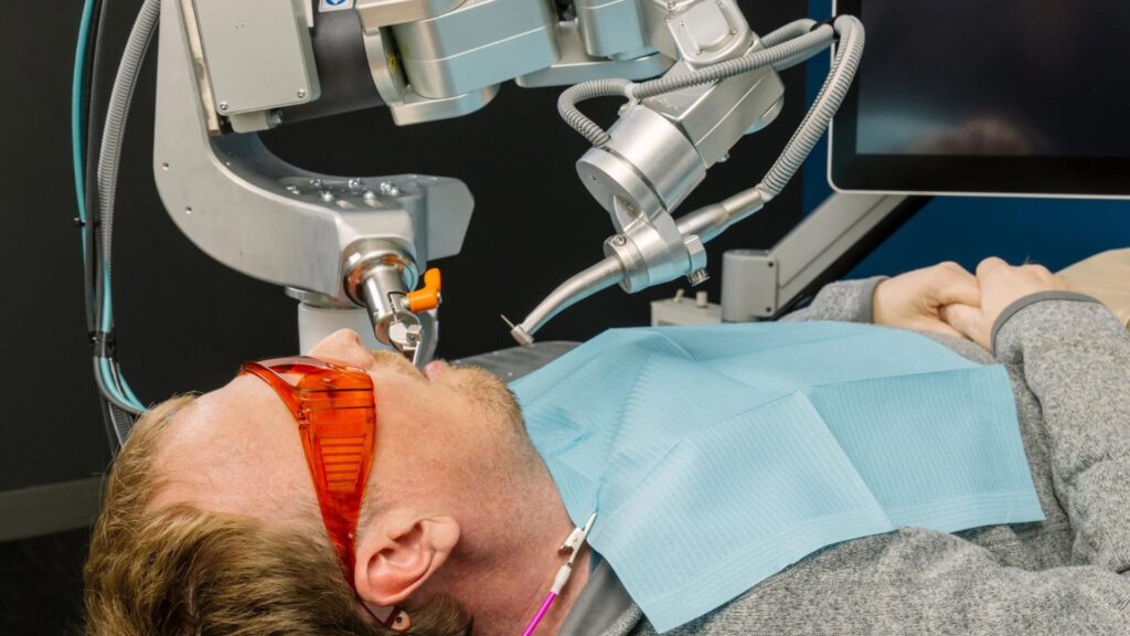 Bras de robot dentaire autonome guidé par l'IA réalisant un soin sur un patient dans un cabinet dentaire moderne