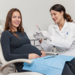 Femme enceinte souriante lors d'un examen de santé dentaire pendant la grossesse dans un cabinet dentaire moderne